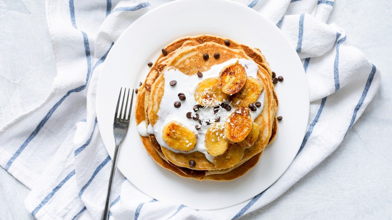 plate of waffles with chocolate chips, coconut, cream, and caramelized bananas