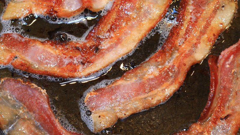 Strips of bacon frying in skillet