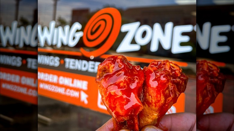 chicken wings held up in front of wing zone store