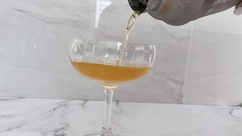 straining cocktail into glass