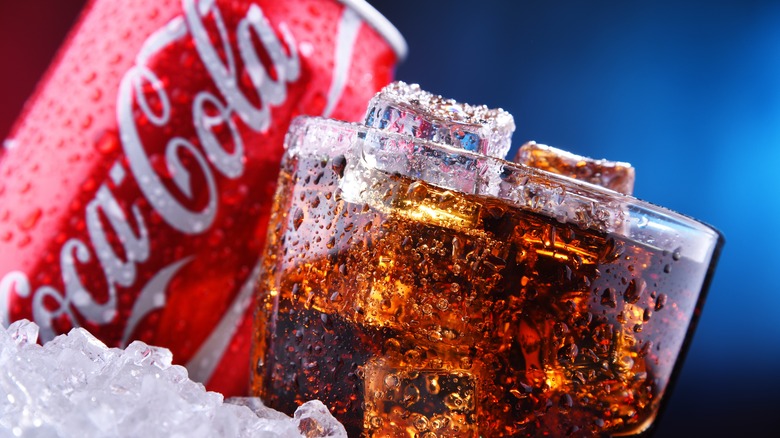 Glass of cola with a can of Coca-Cola