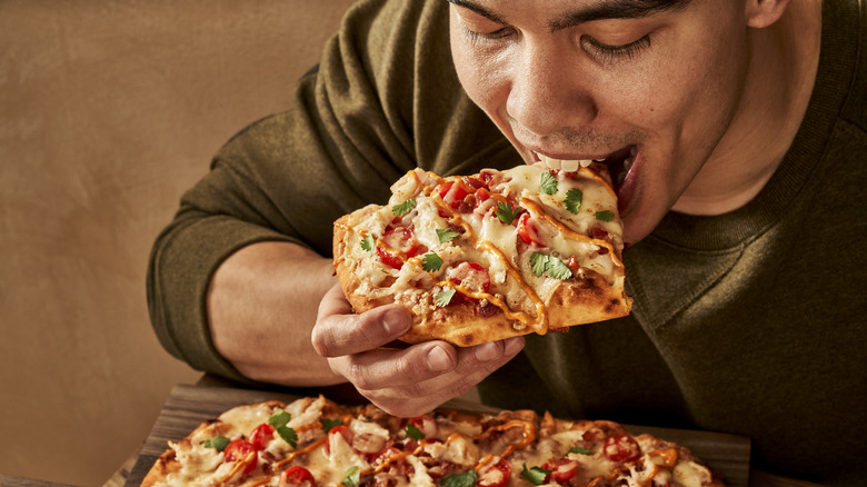 Man takes bite of flatbread pizza