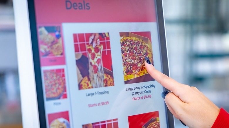 Hand using Pizza Hut ordering kiosk