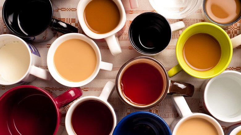 A bunch of half-filled coffee mugs on a table, seen from above