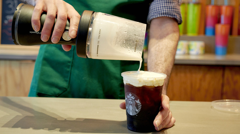 Starbucks employee pouring foam into cup