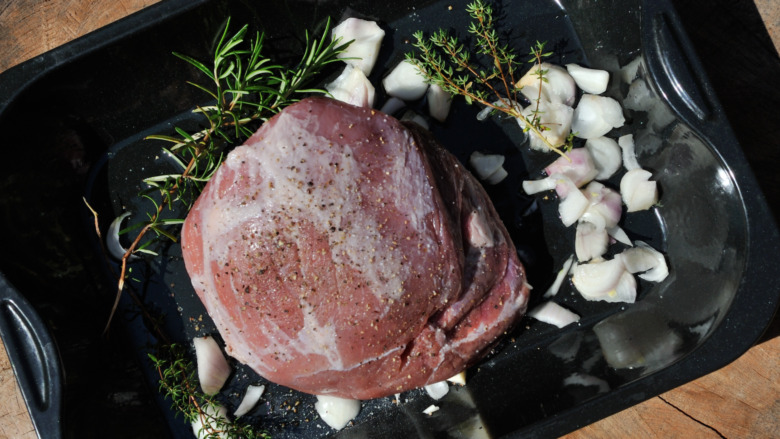 seasoned pork shoulder in pan with herbs