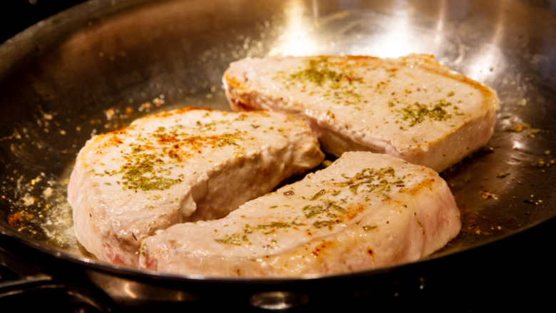 pork chops searing in a pan