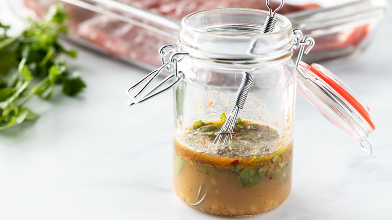 steak in glass dish with basting sauce in glass jar