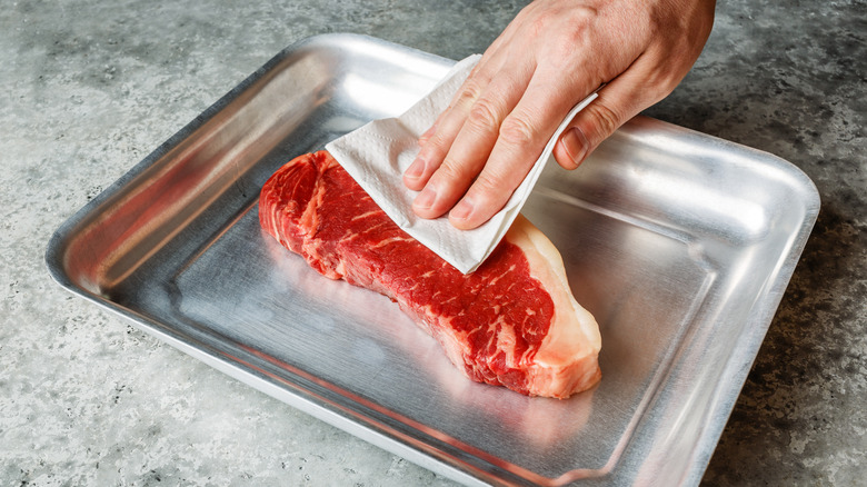 patting dry steak with towel