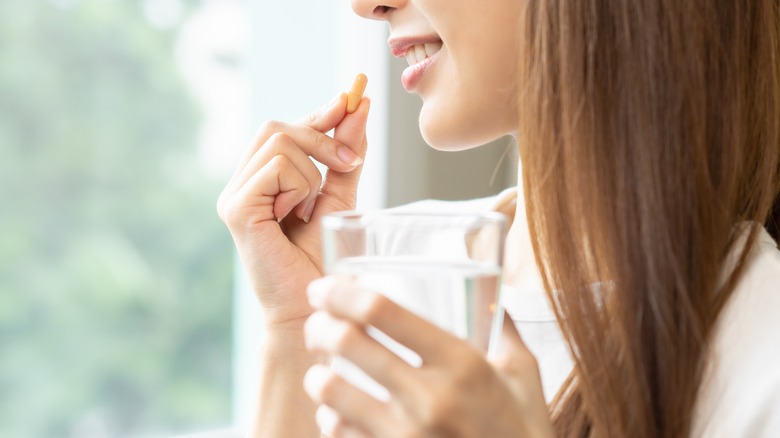 woman taking water with pill