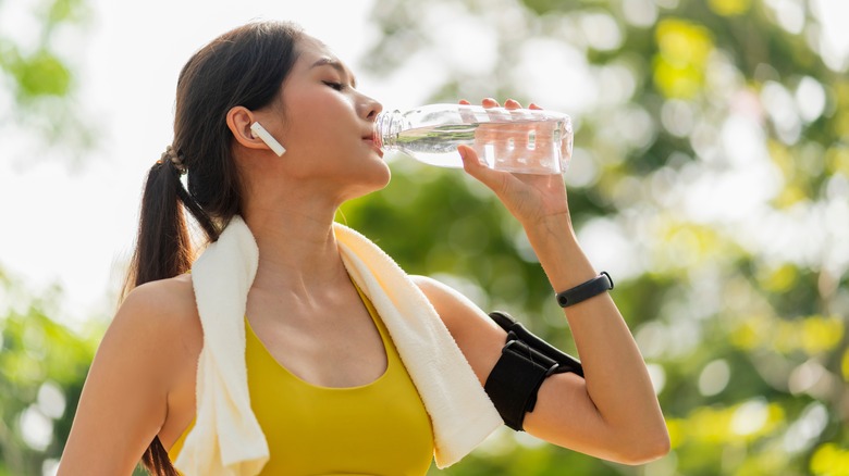 exercising woman drinking water outdoors