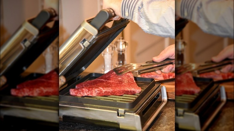 Man placing steak on George Foreman Grill