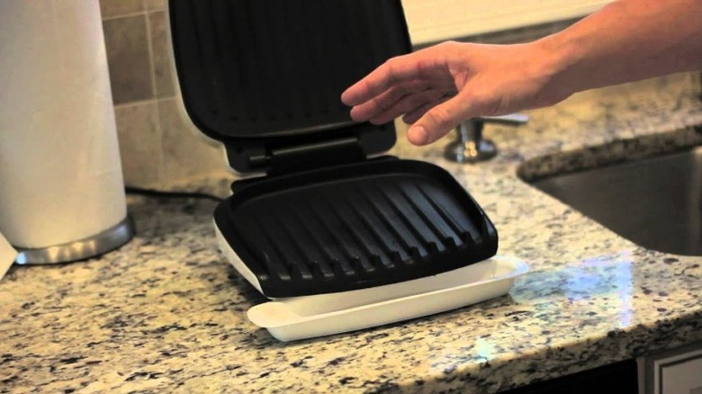 Hand hovering over open George Foreman Grill