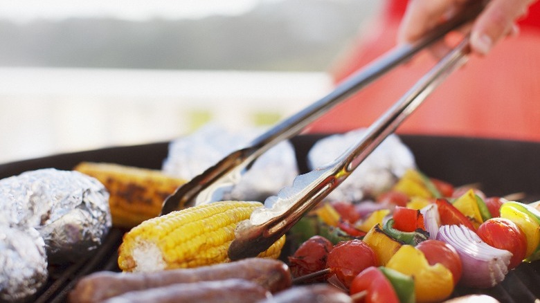 Person placing food on grill with tongs