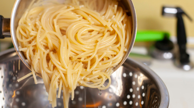 draining pasta in pot with colander