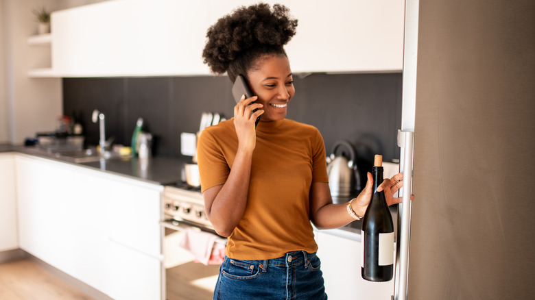 woman taking open wine from fridge