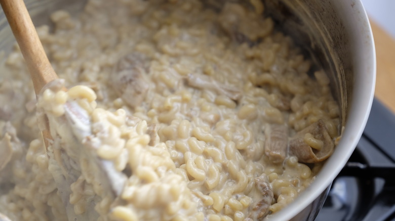 creamy mac and cheese in saucepan with spoon