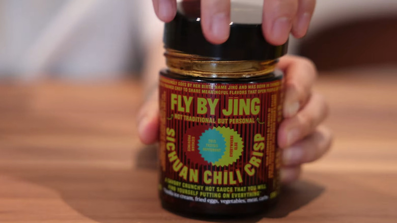 Person opening jar of Fly By Jing