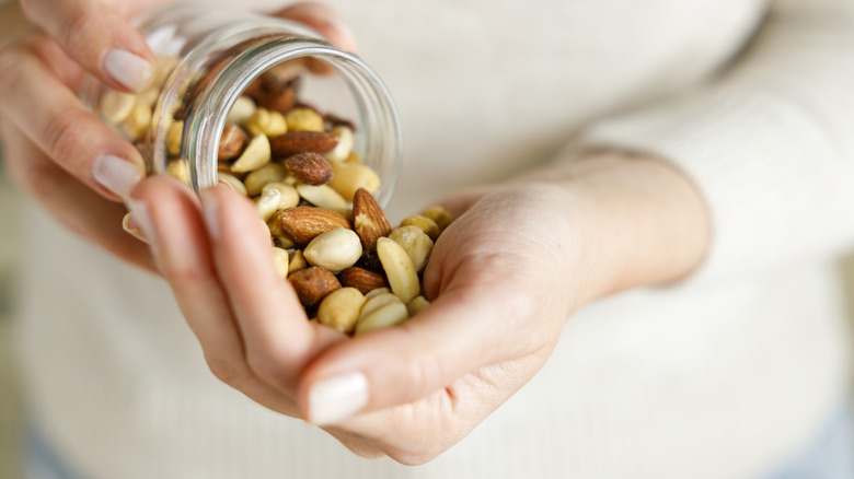 Person pouring handful of nuts