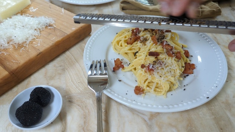 grating truffle over carbonara