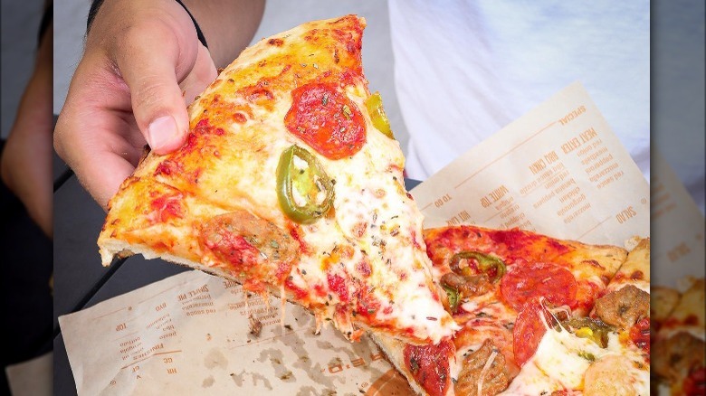 person holding slice of Blaze Pizza