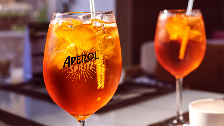 Close up of an aperol spritz in a glass with ice and straw