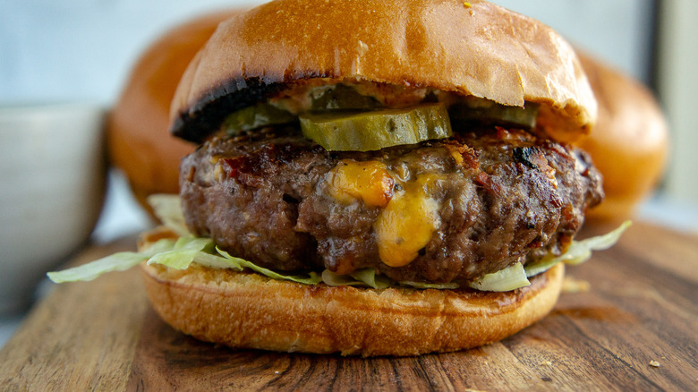 a beef burger stuffed with cheese on a wooden board