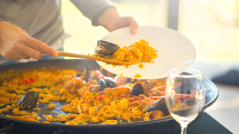 A person putting paella on a dish