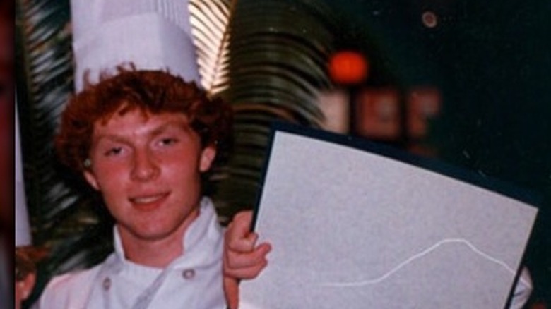 Bobby Flay in his early twenties holding a diploma