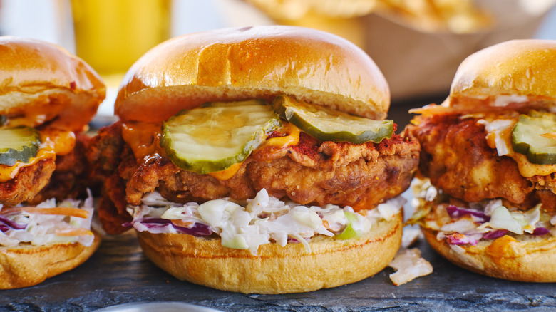 Three fried chicken sandwiches with pickles and coleslaw