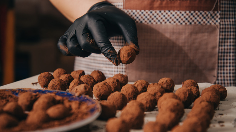 dusting chocolate truffles in cocoa powder