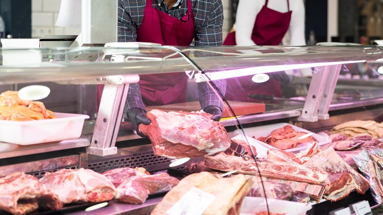butcher holding meat next to woman 