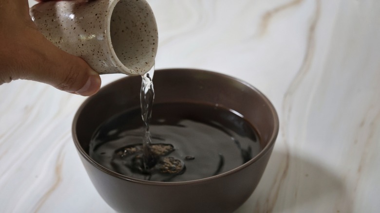 pouring vodka into bowl of coffee