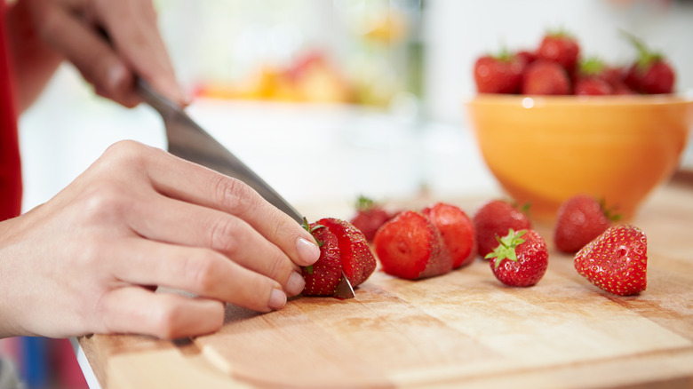 person cutting the stems off strawberries