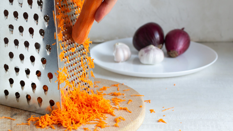 grating a carrot near onions and garlic