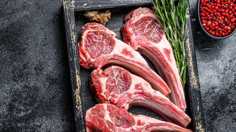 raw lamb with rosemary on black background