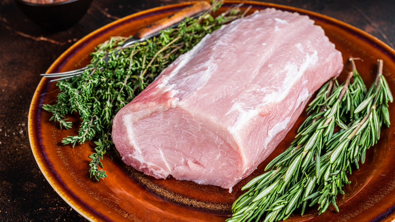 raw pork loin on wooden plate with rosemary