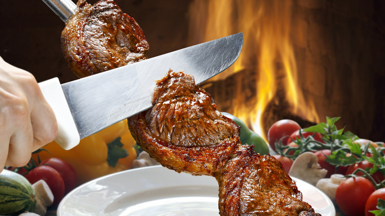 hand holding knife slicing meat