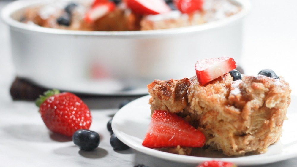 French toast casserole with sliced strawberries and blueberries on a white plate