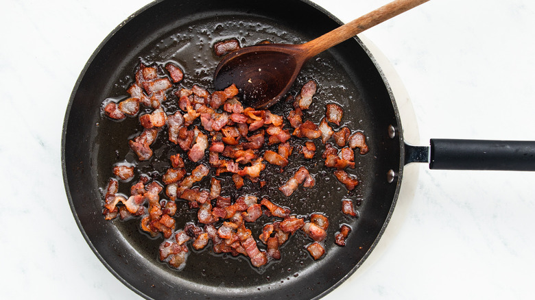 Diced bacon frying in pan