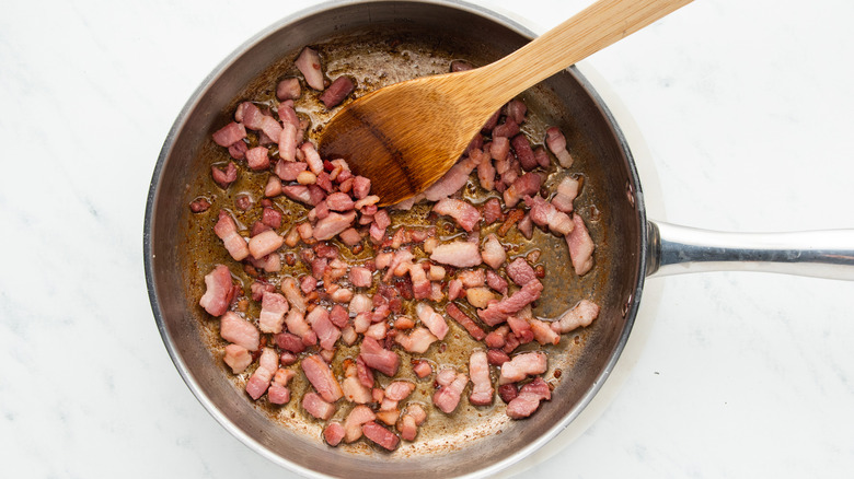 Bacon lardons frying in a pan