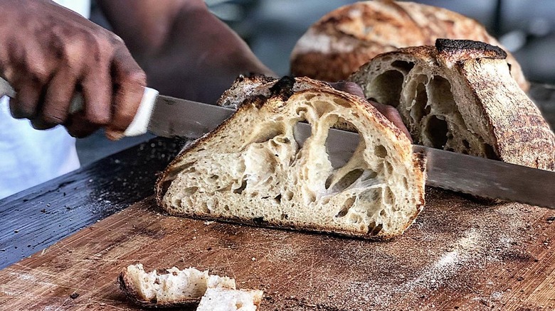 Hand slicing bread with knife