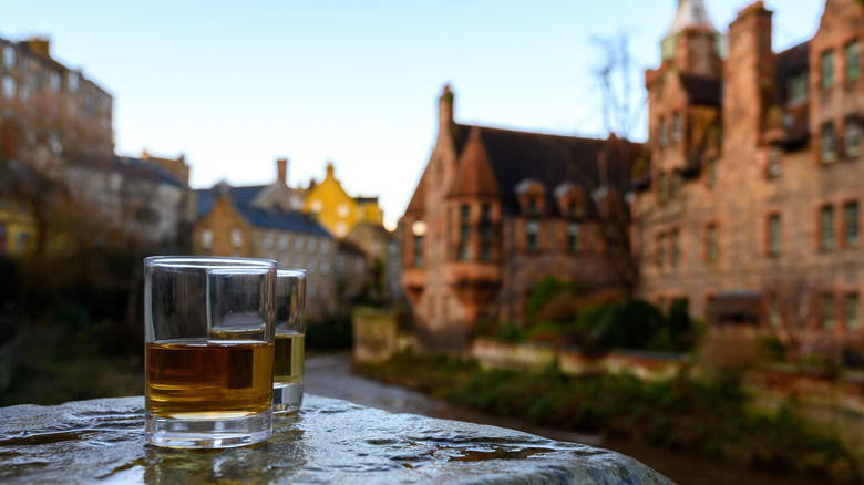 Two glasses of scotch on a rock with old Scottish houses in the background