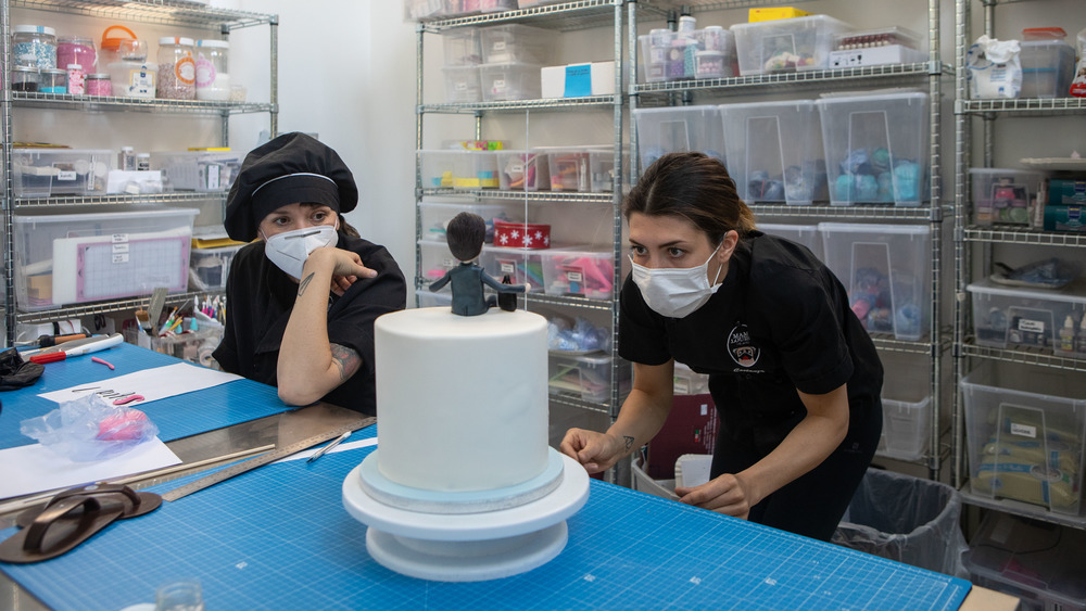 People intricately decorating a cake