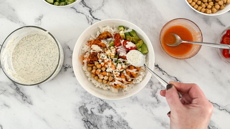 assembling rice bowls with chicken and vegetables