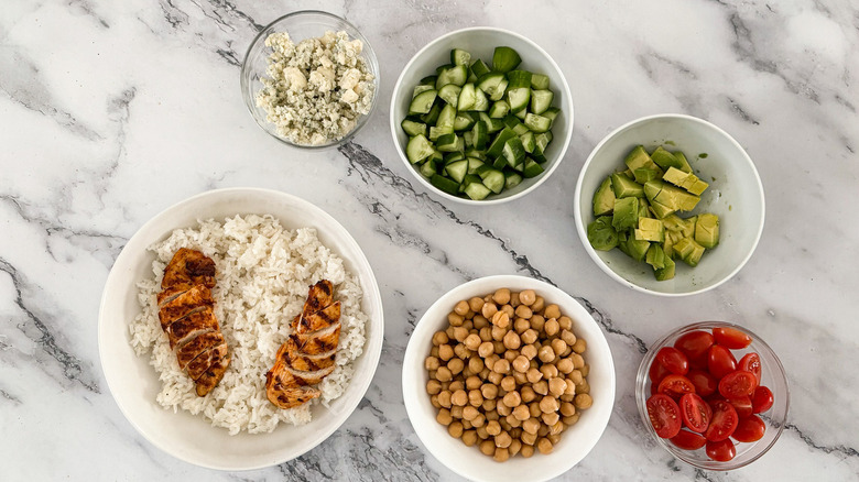 assembling rice bowls with chicken and vegetables