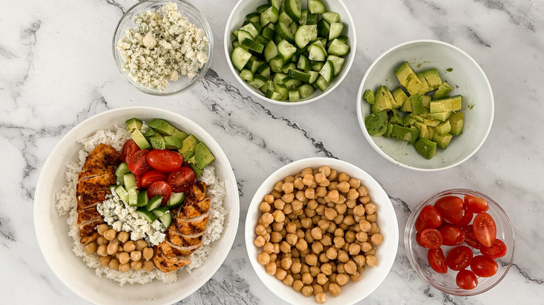 assembling rice bowls with chicken and vegetables