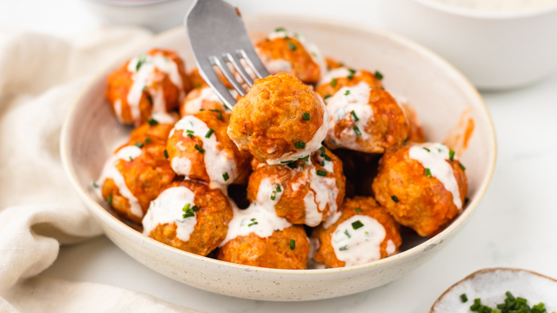 Bowl of buffalo chicken meatballs with one on fork