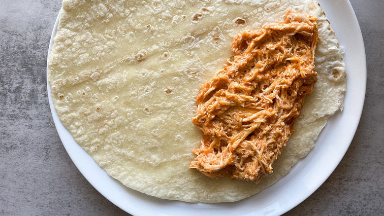 Shredded buffalo chicken spread in a tortilla