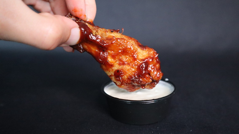 chicken wing being dunked into sauce